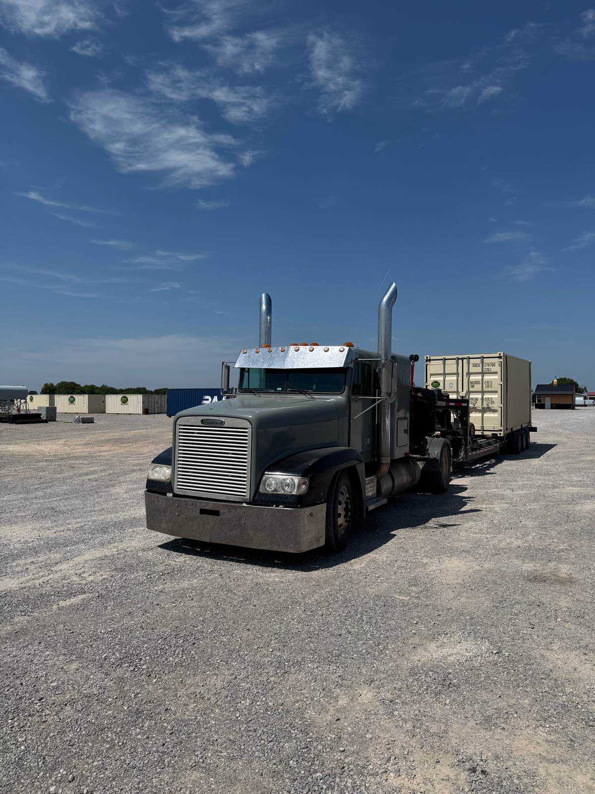 Truck with a tan shipping container at a container lot