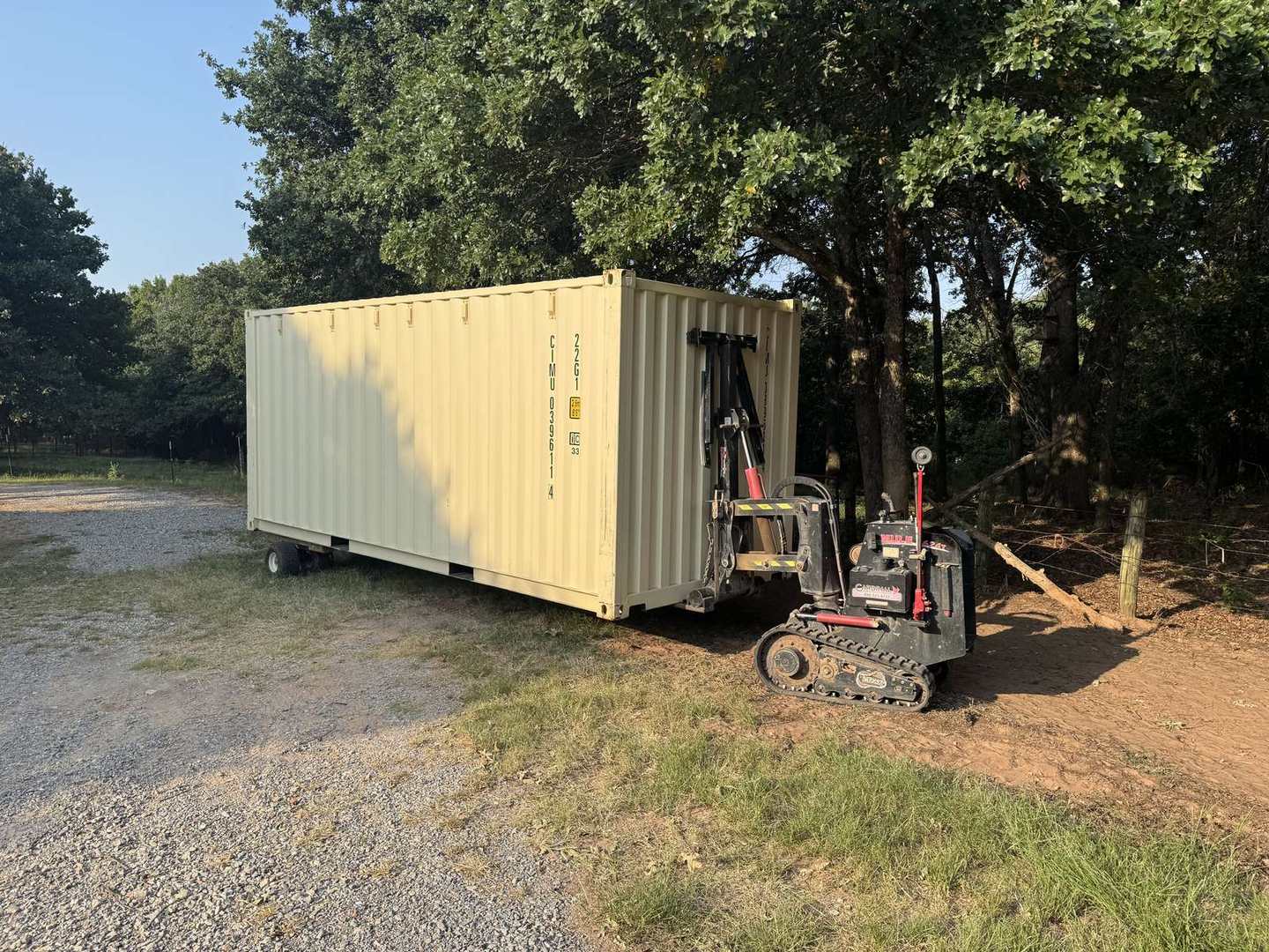 Tan container being set in the trees with a crawler mover